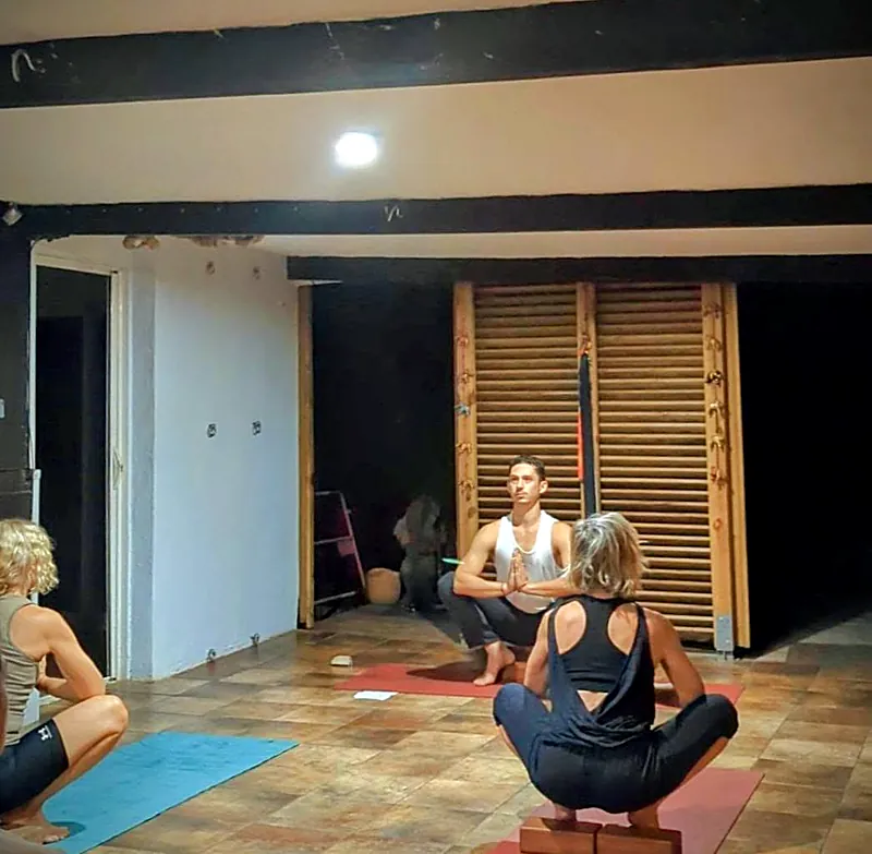 Élève accroupie, une brique sous les talons, pendant un cours de yoga en salle
