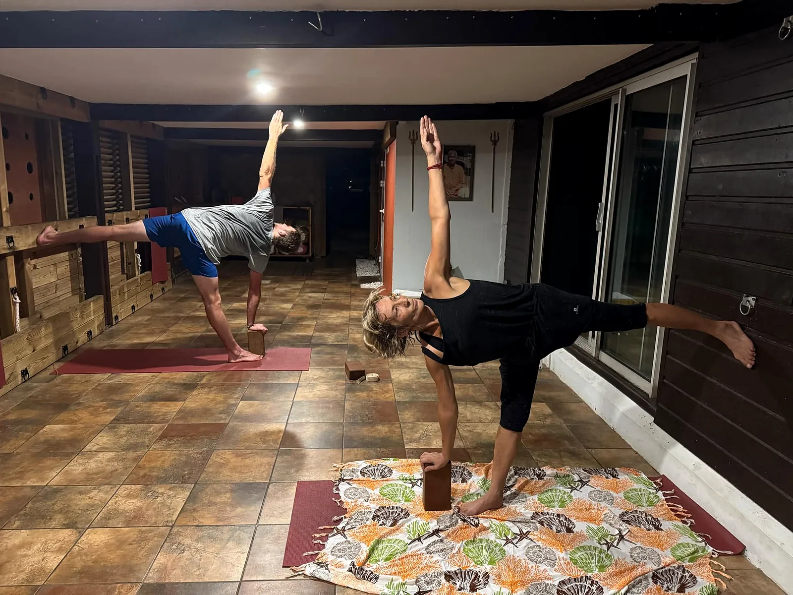Deux élèves en demi-lune, une main posée sur une brique, pendant un cours de yoga