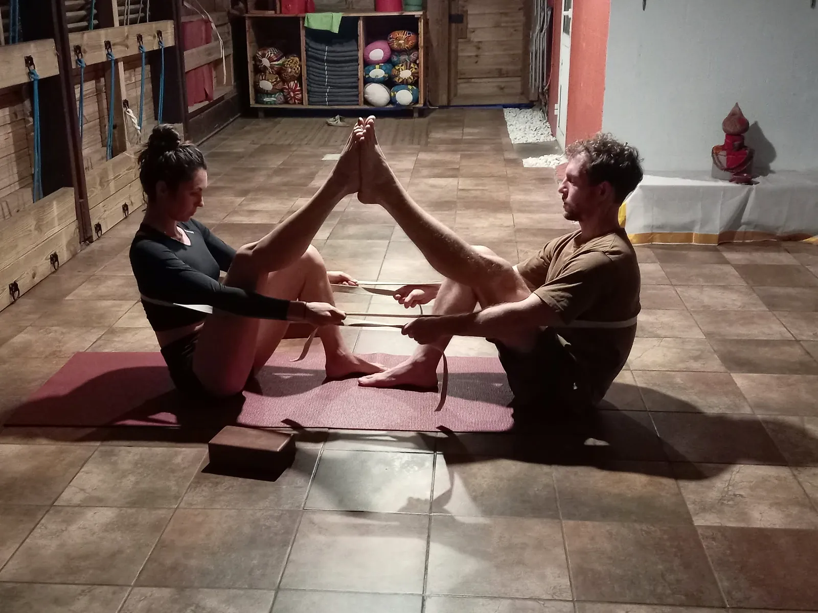 Deux élèves face à face, pieds contre pieds, s'étirent avec une sangle