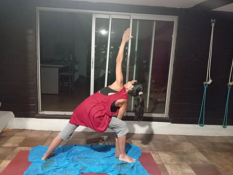 Élève en posture du triangle, un bras tendu vers le ciel